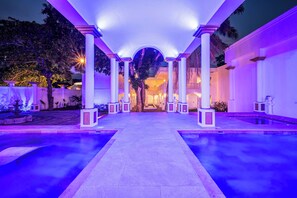 A pool area with a central pathway flanked by columns and a view of a building in the background. - The Palace 10br Villa Luxury Pool, Jacuzzi, Resort Style Bar (Jacó)