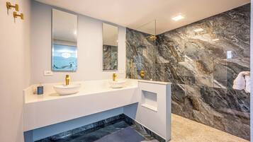 A modern bathroom with two sinks, a large mirror, and a marble wall.