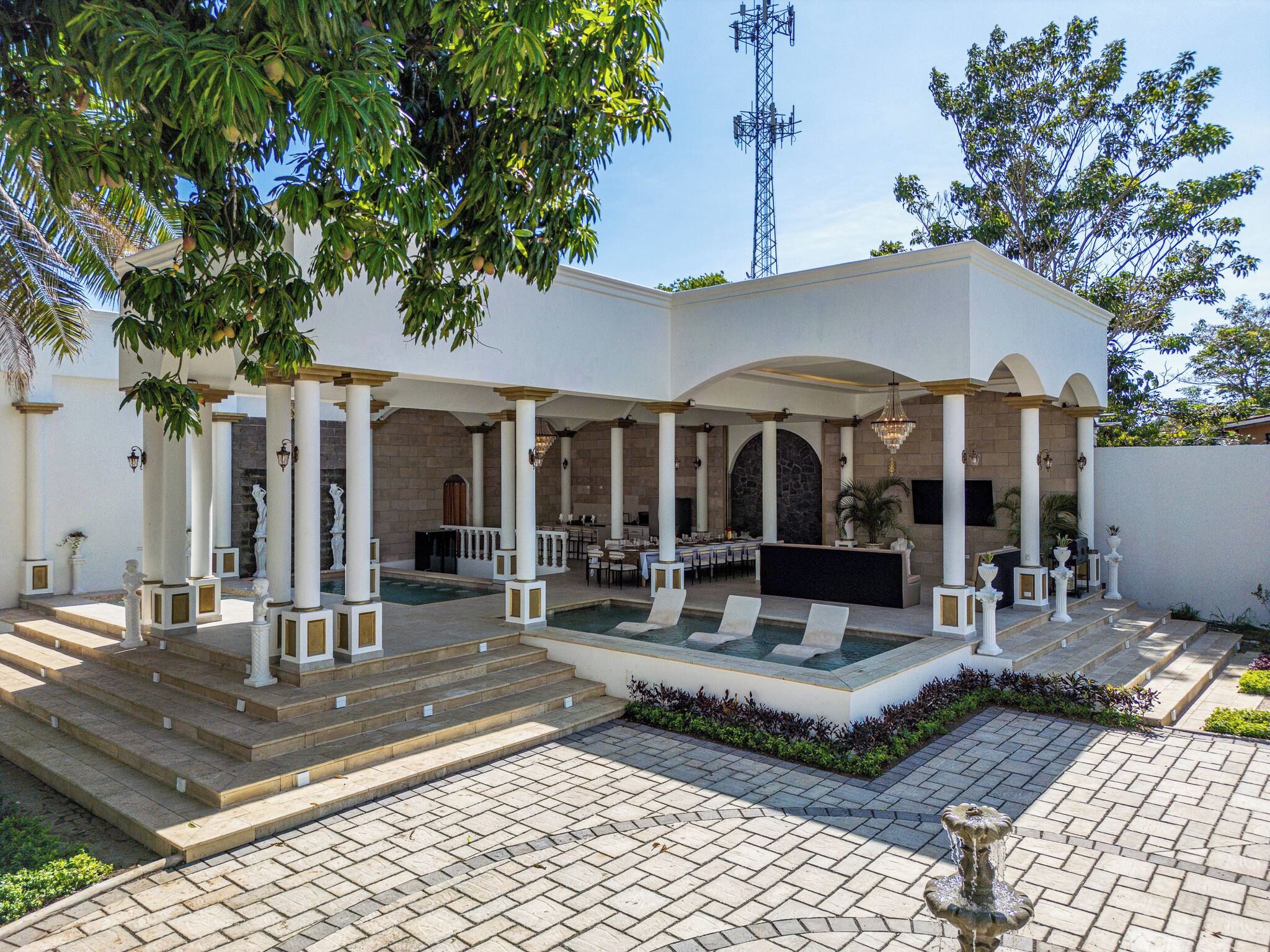 A covered outdoor area with a pool, seating, and a fountain.