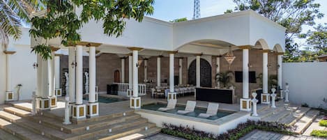 A covered outdoor area with a pool, seating, and a fountain.