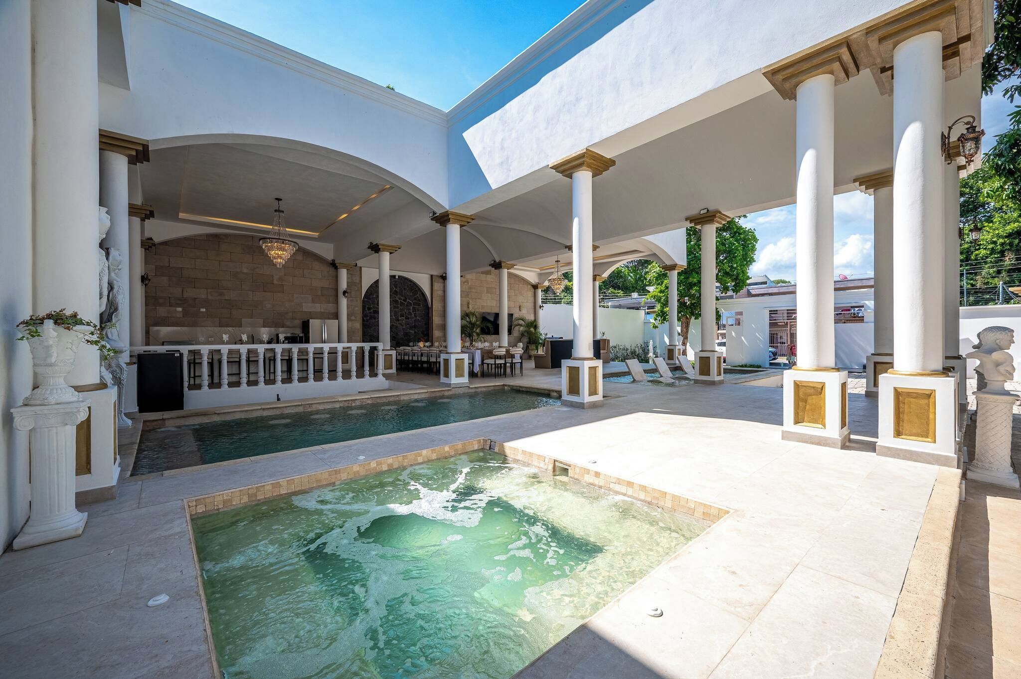 Uma área de piscina com hidromassagem, cercada por colunas e um espaço coberto para relaxar.
