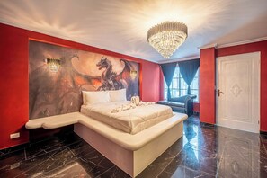 Ein Schlafzimmer mit einem Bett, einem großen Drachenwandgemälde, einer Kristallleuchtre und einer roten Wand.