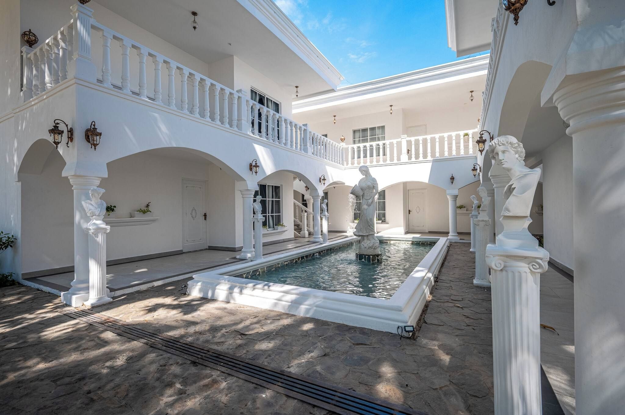 A courtyard with a central fountain, white columns, and arches.