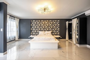 A modern bedroom with a large bed, a decorative wall, and a chandelier. - The Palace 10br Villa Luxury Pool, Jacuzzi, Resort Style Bar (Jacó)