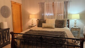 Ein Schlafzimmer mit Bett, Nachttischlampen, einer Holztür und einer Wanddekoration.