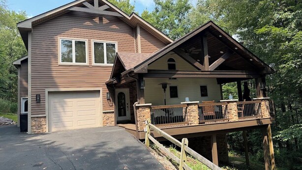 Ein zweistöckiges Haus mit Garage, überdachter Veranda und Natursteinfassade.