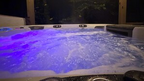 Ein Whirlpool mit blauem Licht, umgeben von Holzbalken und Lichterketten.