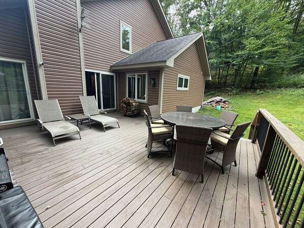 A deck with outdoor furniture, a fire pit, and a house with a sloped roof.