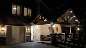 Ein zweistöckiges Haus mit Garage, Steinaußenwand und überdachter Veranda mit Sitzgelegenheit.