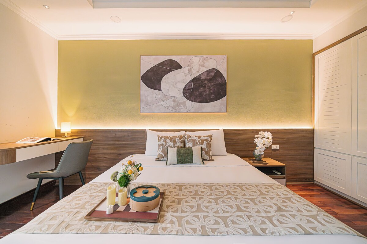 A modern hotel room with a large bed, a desk, and a chair.