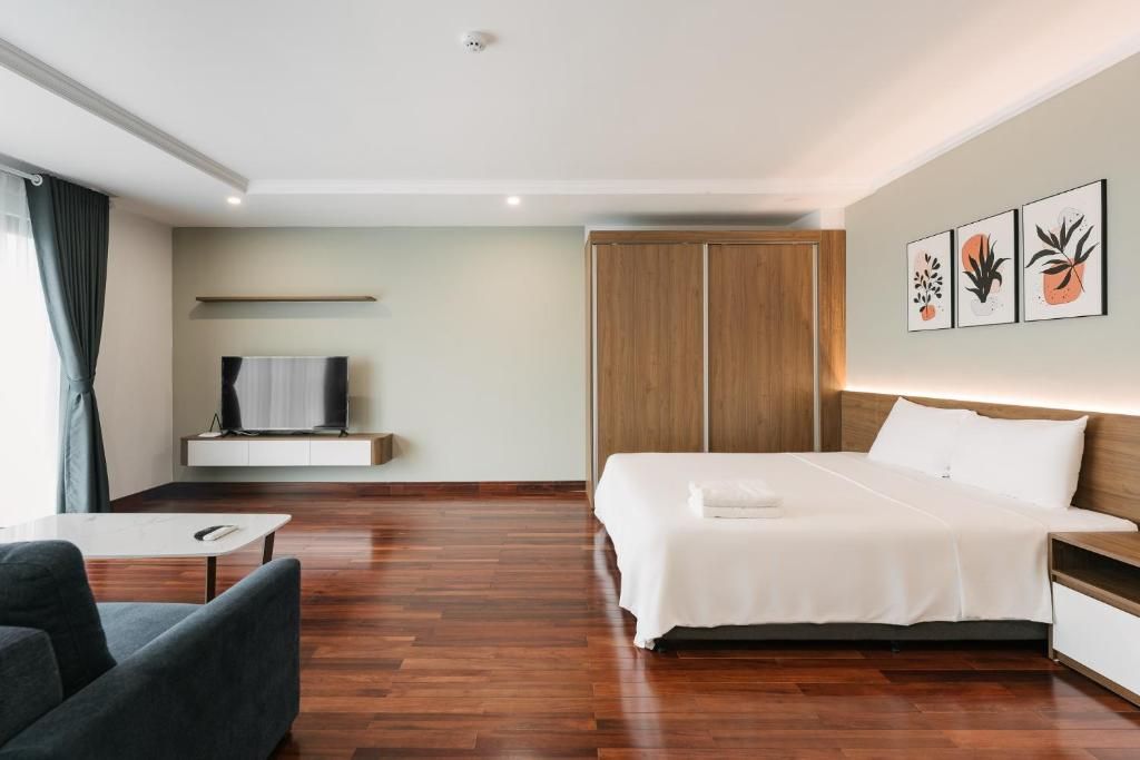 Een moderne hotelkamer met een groot bed, een televisie op een plank, een kledingkast en kunst aan de muur.