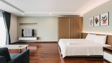 Een moderne hotelkamer met een groot bed, een televisie op een plank, een kledingkast en kunst aan de muur.