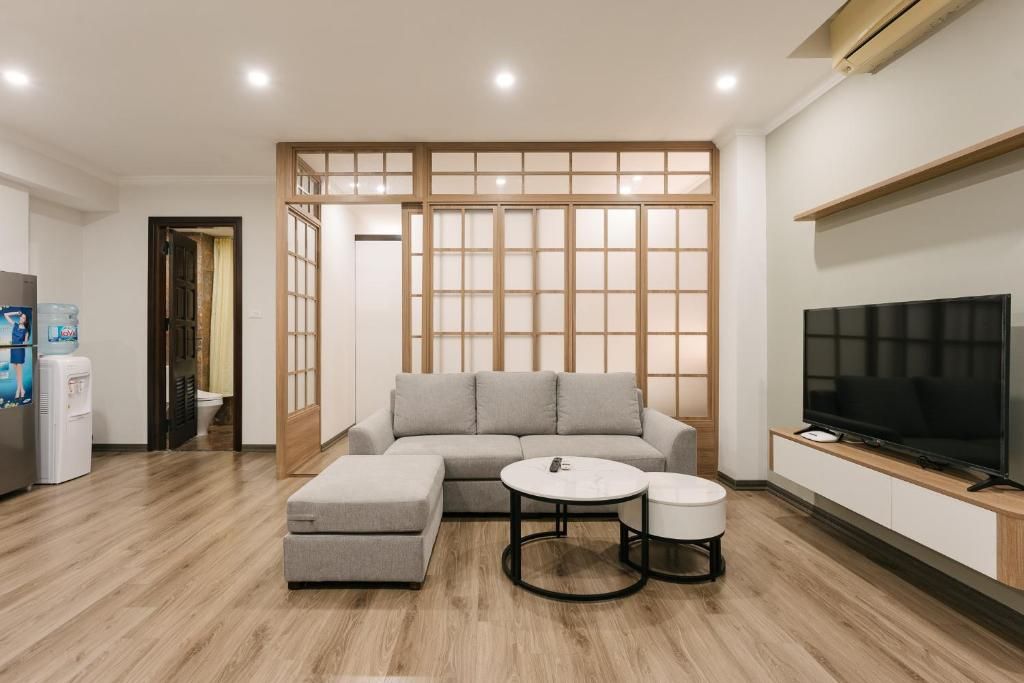 A modern living room with a sofa, ottoman, coffee table, and TV.
