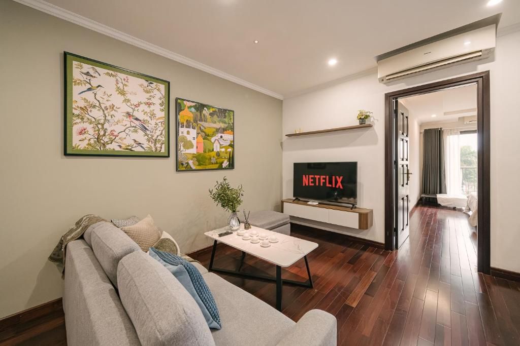 A modern living room with a sofa, a coffee table, and a flat-screen TV mounted on a wall.