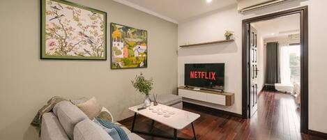 A modern living room with a sofa, a coffee table, and a flat-screen TV mounted on a wall.