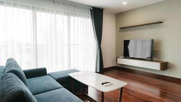 Un salon moderne avec un canapé, une petite table, un téléviseur à écran plat et un plancher en bois.