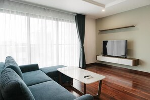 A modern living room with a sofa, a small table, a flat-screen TV, and a wooden floor. - Hanoi Lux Lakeside Hotel and Apartment (Giang Vo)