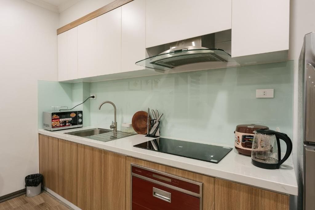 Una cocina moderna con un lavamanos de acero inoxidable, un microondas y un hervidor en la encimera.