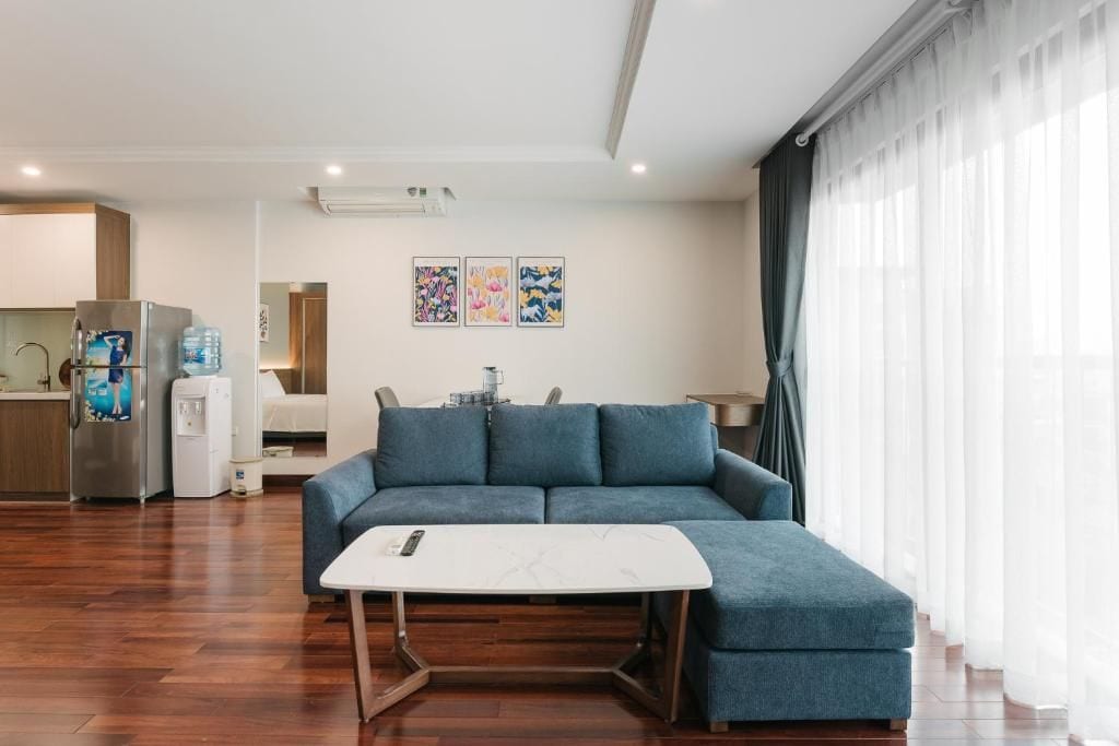 A modern living room with a sofa, a coffee table, and a kitchen area in the background.