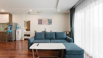A modern living room with a sofa, a coffee table, and a kitchen area in the background.