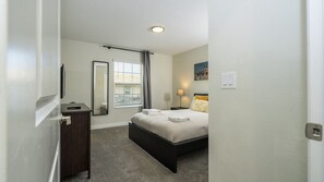 A bedroom with a bed, bedside table, lamp, and a window with blinds. - 4BR Storey Lake Private Pool & BBQ Near Disney (Kissimmee)