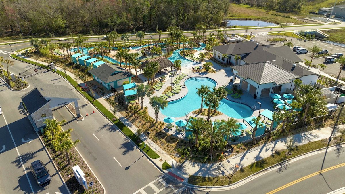 A resort with a swimming pool, lounge areas, and a parking lot.