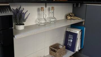 A kitchen shelf with glass bottles, a framed picture, and a coffee maker.
