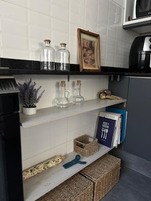 Uno scaffale da cucina con bottiglie di vetro, una cornice con un'immagine e una macchina da caffè.