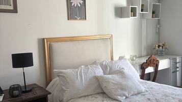 A neatly made bed with a floral bedspread, a bedside lamp, and a framed picture on the wall.