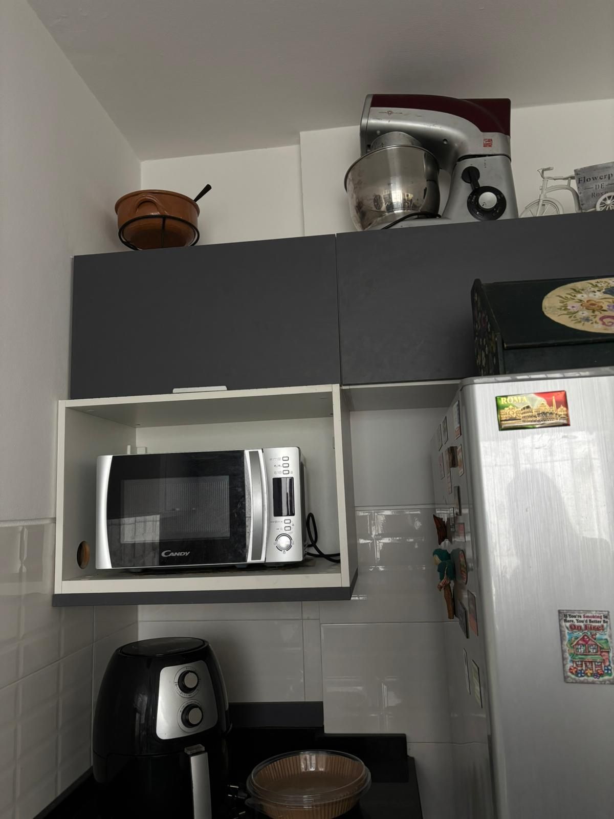 Una cocina equipada con microondas, tostadora y refrigerador.