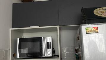 Una cocina equipada con microondas, tostadora y refrigerador.
