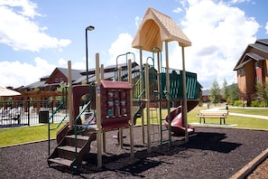 Ein Spielplatz mit Rutsche, Kletterbereich und einem überdachten Spielhäuschen.