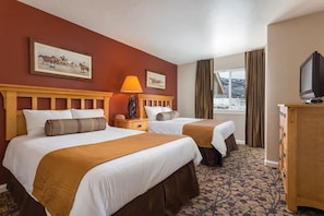 Una habitación de hotel con dos camas, televisión, cómoda y ventana con cortinas.