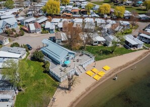 Ett bostadsområde med flera hus, en stor byggnad med ett blått tak och en sandstrand med gula parasoller.