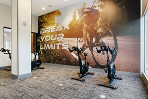 A gym with stationary bikes, a wall with motivational text, and a window with a view of a road. - Cozy Chic Downtown Birmingham Studio  Free Parking Near Dining & Entertainment (Birmingham)