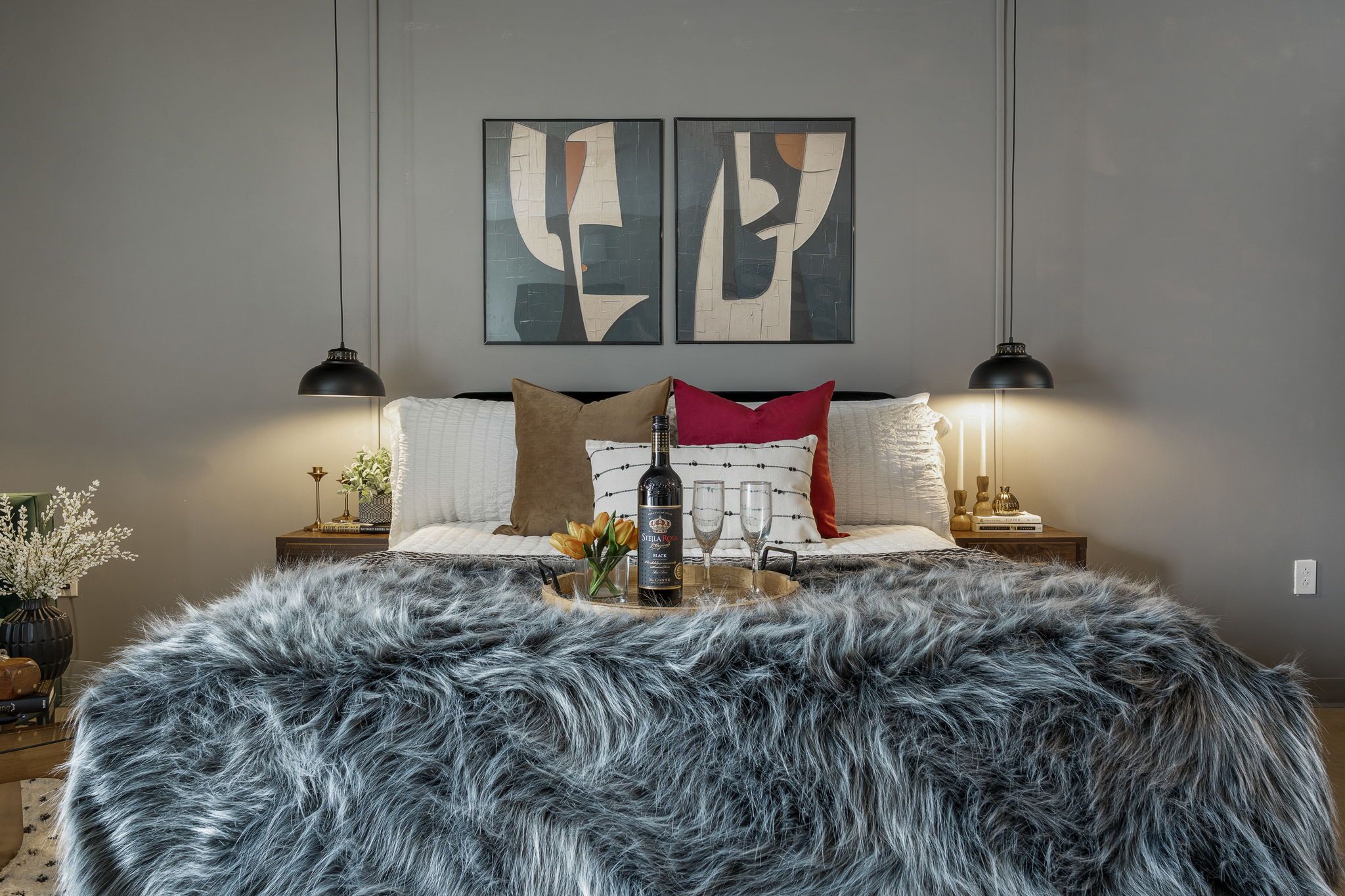 A bedroom with a bed, two nightstands, a fluffy rug, and abstract wall art.