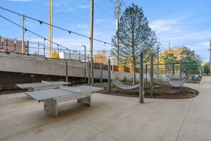 An outdoor area with a ping pong table, hammock, and a tall tree. - Cozy Chic Downtown Birmingham Studio  Free Parking Near Dining & Entertainment (Birmingham)
