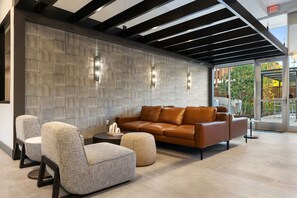 A modern interior with a brown leather sofa, patterned armchairs, and a textured wall. - Cozy Chic Downtown Birmingham Studio  Free Parking Near Dining & Entertainment (Birmingham)