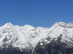 Ein verschneites Gebirge mit spitzen Gipfeln unter blauem Himmel.