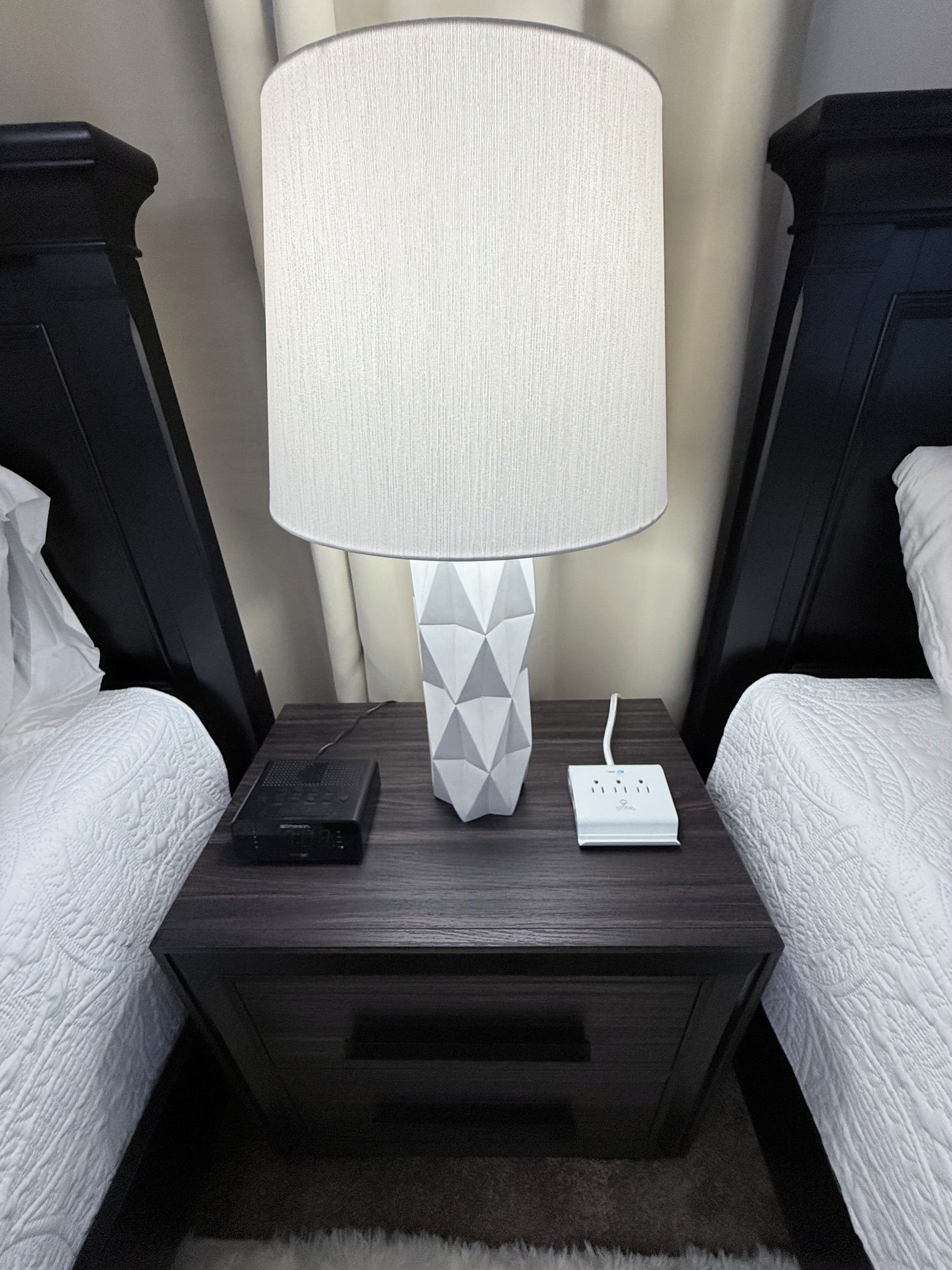 Une chambre d’hôtel équipée d’une table de chevet, d’une lampe, d’une multiprise et de deux lits.