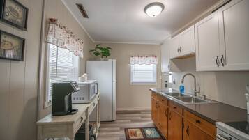 Cocina compacta con refrigerador, microondas, lavamanos y armarios de madera.