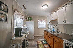 Cocina compacta con refrigerador, microondas, lavamanos y armarios de madera.