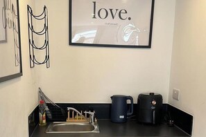 A kitchen with a sink, a kettle, and a coffee maker. - Studio Sleeps 2 with WiFi (Thornton Heath)