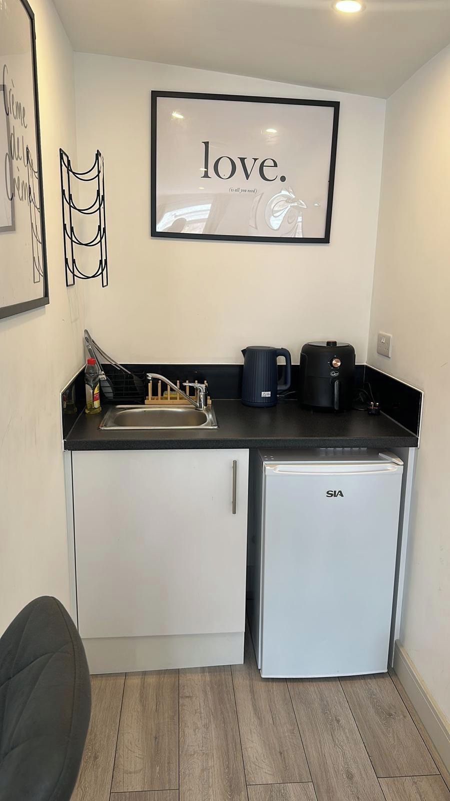 A compact kitchenette with a refrigerator, coffee maker, and sink.