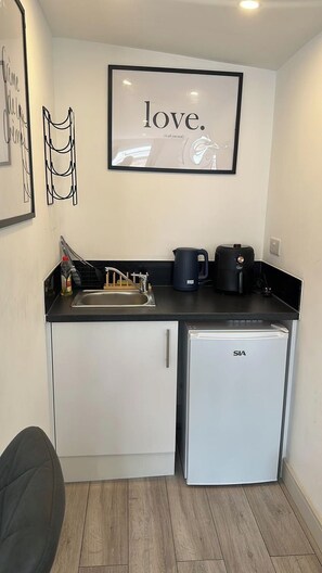 A compact kitchenette with a refrigerator, coffee maker, and sink. - Studio Sleeps 2 with WiFi (Thornton Heath)