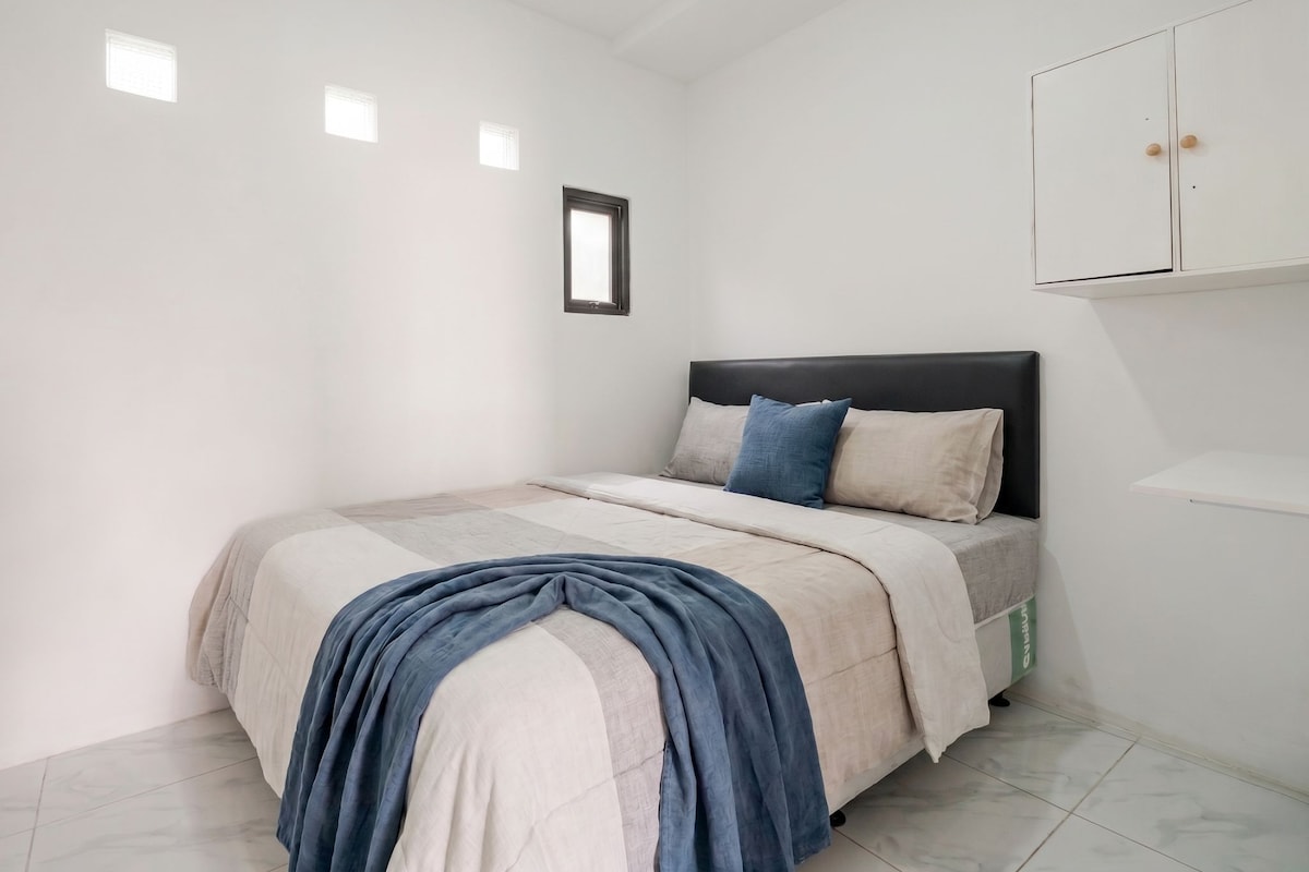Un dormitorio con cama, armario y ventana.
