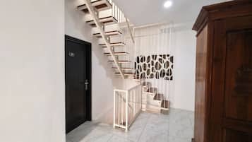 A modern staircase with a white railing, a black door with a number, and a patterned wall.