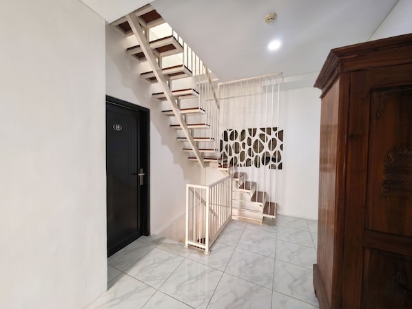 Una escalera moderna con barandilla blanca, una puerta negra con un número y una pared con diseño.