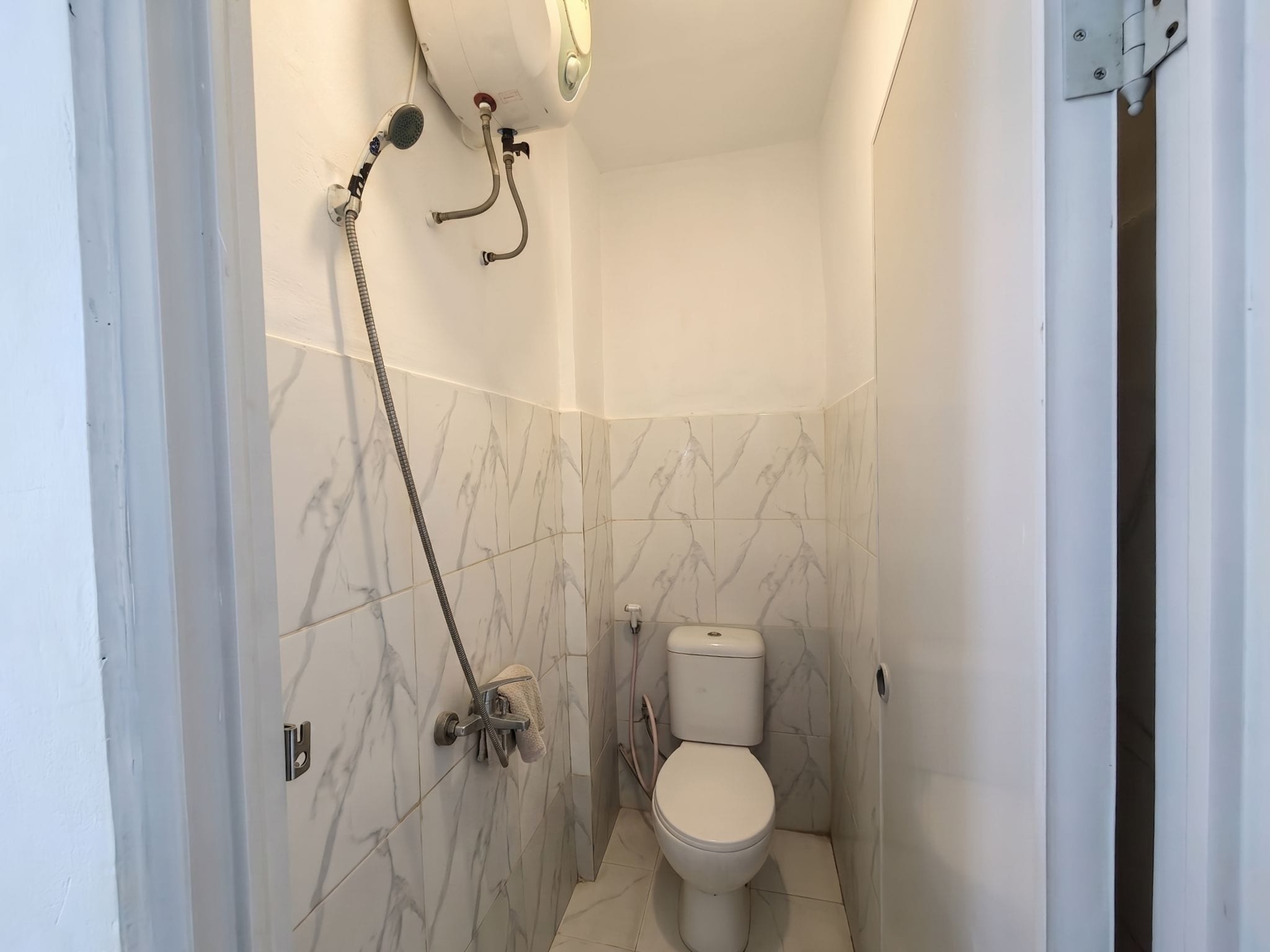 A small bathroom with a toilet, a shower, and a towel rack.