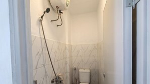 Une petite salle de bain comprenant des toilettes, une douche et un porte-serviettes.